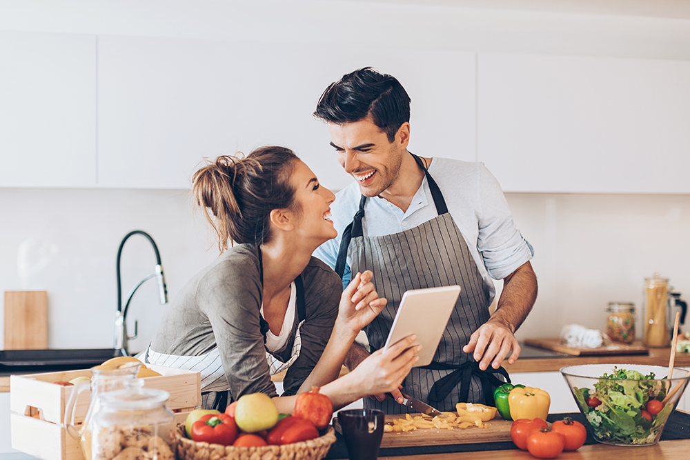 Lovely couple with digital tablet and fresh vegetables in the kitchen.